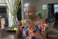 Portrait of smiling woman holding cup of tea in living room