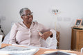 Smiling senior woman sitting on bed, holding remote control