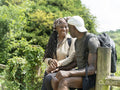Smiling mature couple sitting on fence on hike