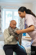 Nurse helping senior man to get dressed at nursing home