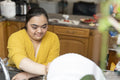 Young woman with down syndrome washing dishes at home