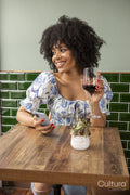 Smiling woman with glass of red wine and smart phone at cafe table