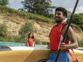 Woman looking at man carrying paddleboard and oar