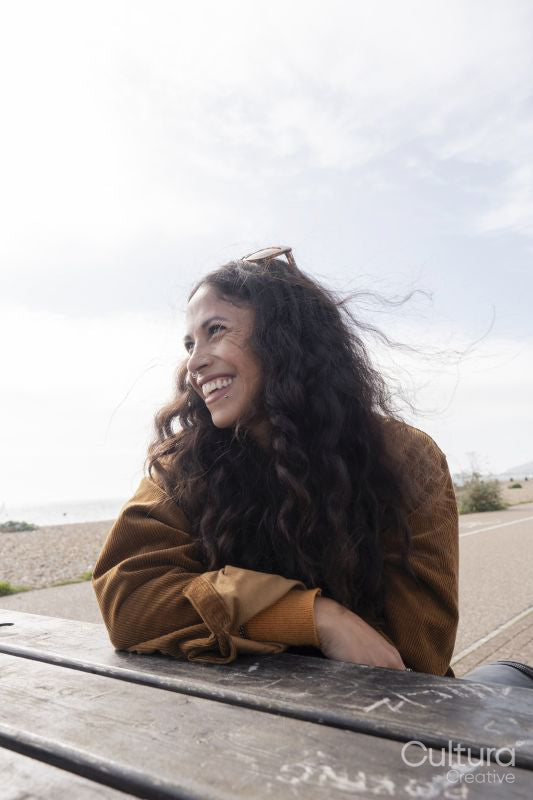 Smiling woman looking away while sitting by picnic table