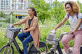 Two women cycling together in city