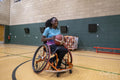 Teenage girl in wheelchair practicing basketball