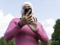 Sutton,Low angle view of woman in headscarf holding smart phone in park