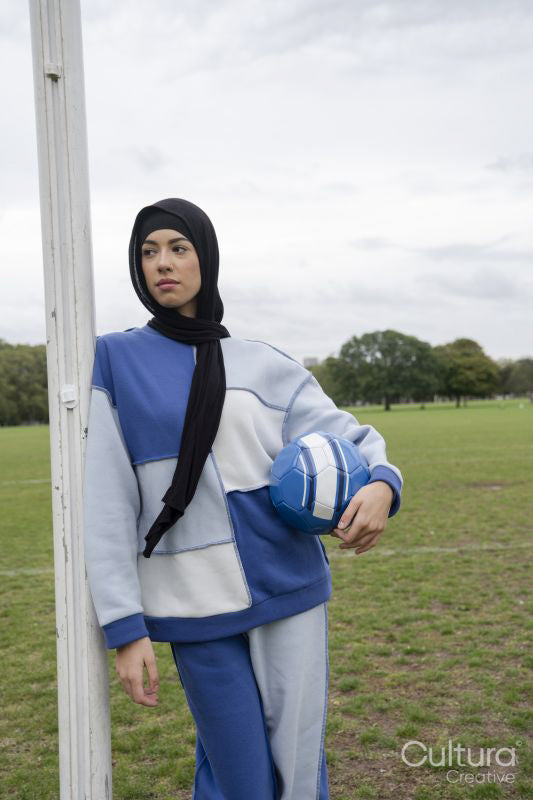 Portrait of woman in hijab standing in soccer field with soccer ball