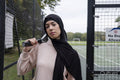 Portrait of woman in hijab holding tennis racket at tennis court