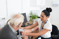 Female doctor taking senior patients blood pressure in office
