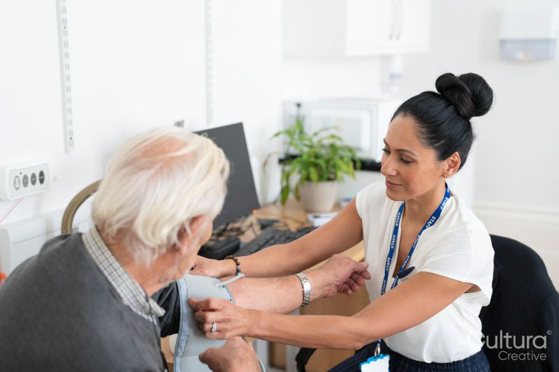 Female doctor taking senior patients blood pressure in office