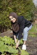 Woman wearing hijab harvesting vegetables in garden