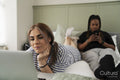 Two young women on bed using mobile devices