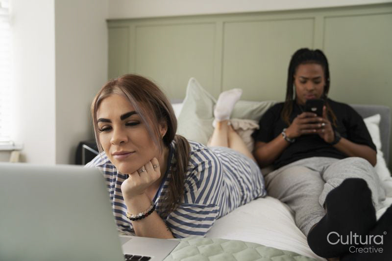 Two young women on bed using mobile devices