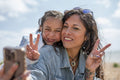 Mother and daughter doing peace sign and taking selfie