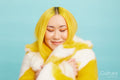 Woman with long yellow hair and closed eyes, wearing fur coat