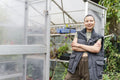 Portrait of smiling woman standing in front of greenhouse
