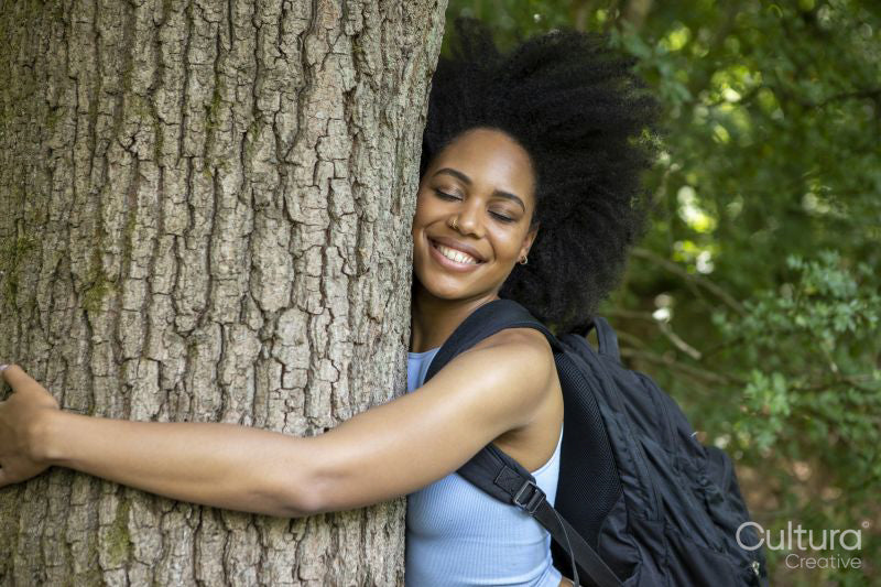Young woman hiking in forest, hugging tree