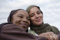 Portrait of smiling Muslim women against cloudy sky