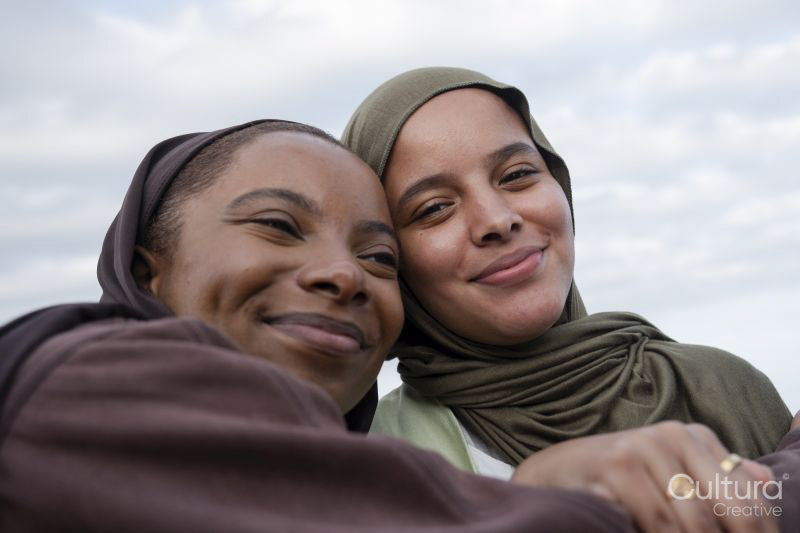 Portrait of smiling Muslim women against cloudy sky
