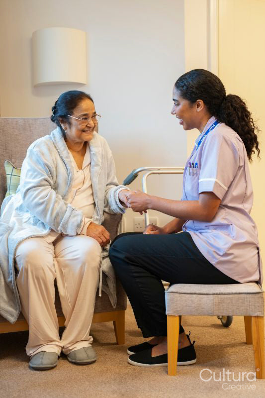 Nurse talking with senior lady in her room at nursing home