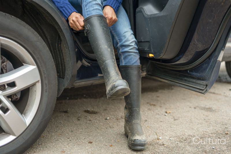 Man sitting on back seat and putting on rubber boot