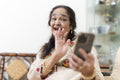 Portrait of senior woman waving to smart phone during video call in living room