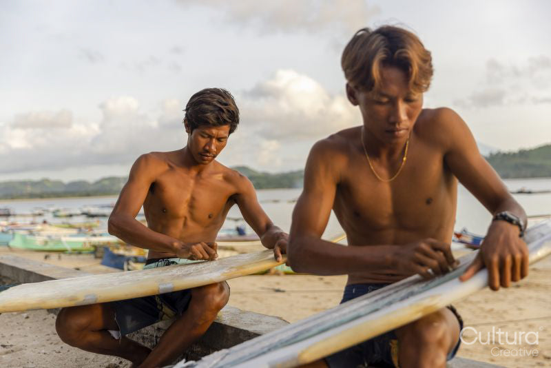 Indonesia, Lombok, Surfers preparing surfboards on beach at sunset