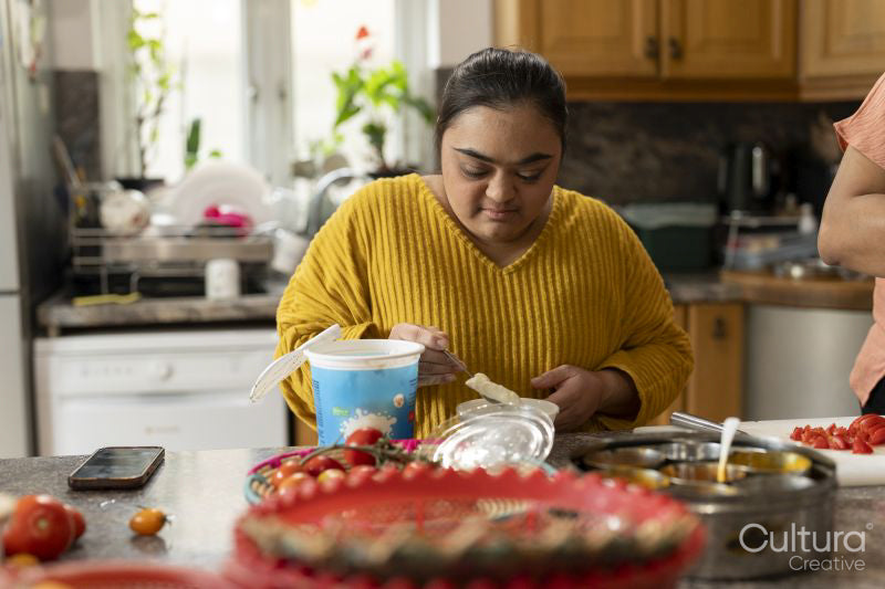Young woman with down syndrome preparing food in kitchen