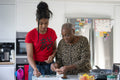 Woman and teenage girl preparing meal in kitchen