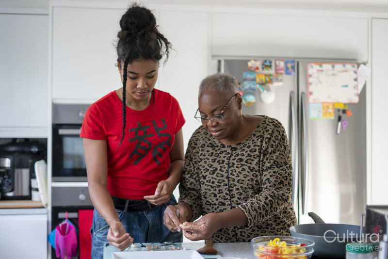Woman and teenage girl preparing meal in kitchen