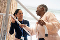Smiling female therapist assisting senior woman ascending steps in exercise room