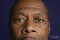 Close-up of man looking at camera against purple background