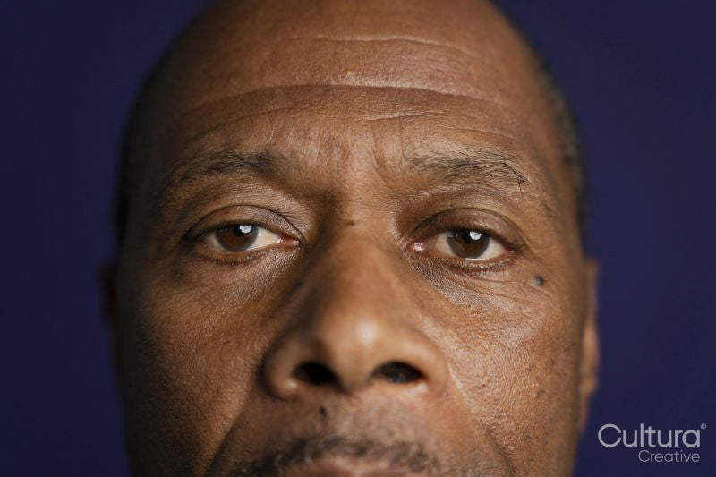 Close-up of man looking at camera against purple background
