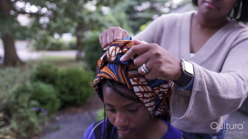 Mother putting traditional headdress on daughter