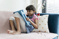 Little girl using tablet while sitting on sofa
