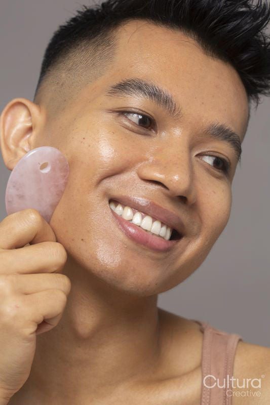 Close-up of smiling person using rose quartz guasha
