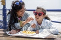 Mother and daughter eating fish and chips at seaside