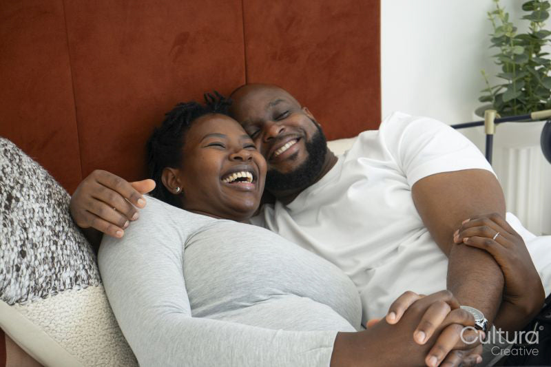 Smiling man embracing pregnant woman on bed