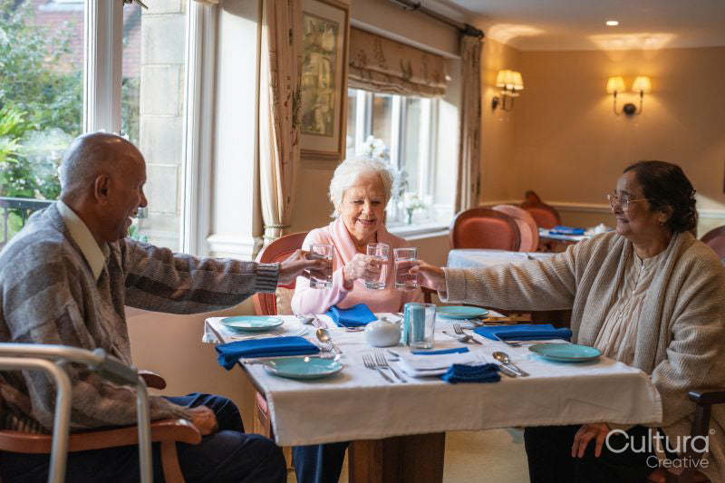 Senior people toasting with water during meal in nursing home