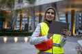 Female engineer in hijab and reflective clothing using tablet