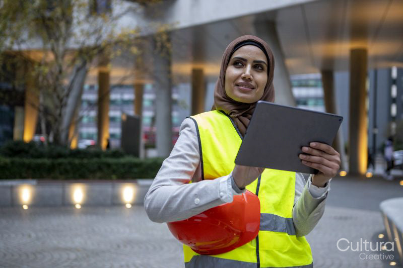 Female engineer in hijab and reflective clothing using tablet