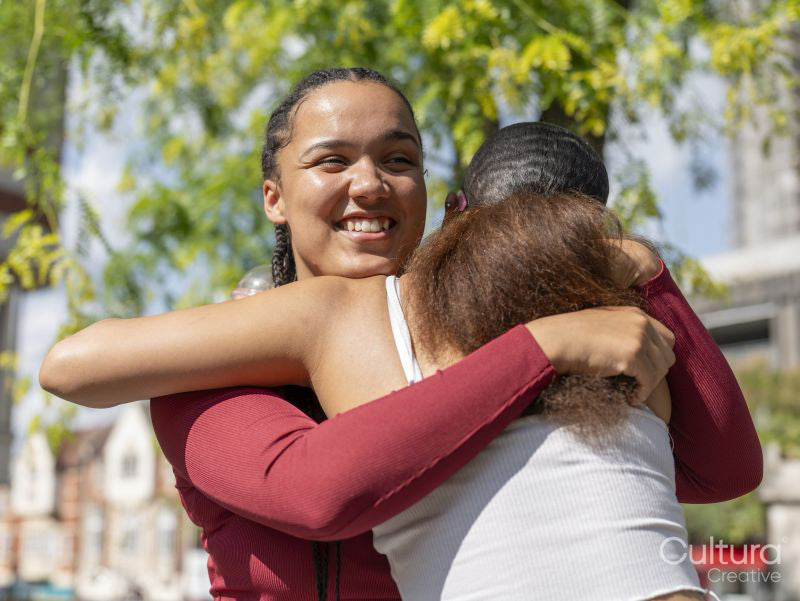 Two female friends embracing on sunny day