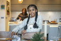 Smiling girl placing Christmas cracker on table, mother in background