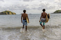 Indonesia, Lombok, Rear view of two surfers walking into sea
