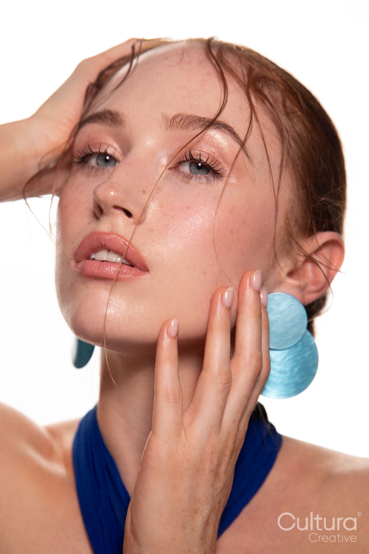 Studio portrait of a woman in a blue dress and large blue earrings