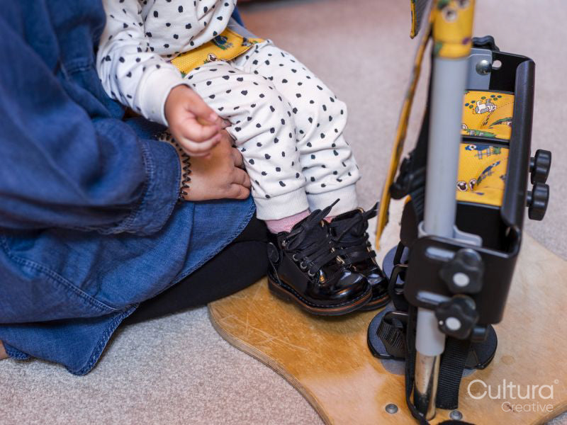 Mother putting daughter in standing frame