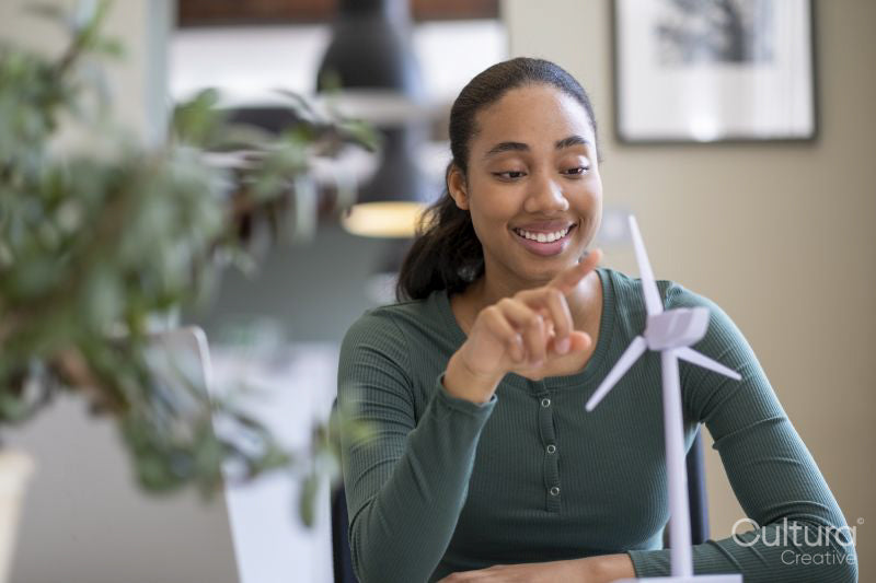Young engineer playing with wind turbine model in office