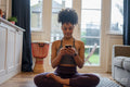 Young woman doing yoga and using phone at home