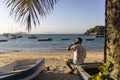 Rear view of man sitting at beach talking on phone